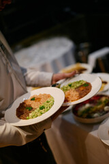The bartender carries plates with different types of tartare