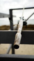 Rustic fishing rod resting on a wooden rack by the seaside on a cloudy day