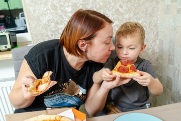 Happy mother and son eating the delicious pizza at home