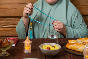 A woman in a light green hijab at a table with dates fingering