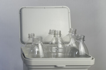 Transparent Plastic Bottles in White Recycling Bin, Eco-Friendly Concept, Against Neutral Background