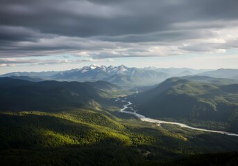 Obraz premium Majestic Mountain Panorama: A Serene River Valley Nestled Amongst Verdant Hills Under a Dramatic Sky