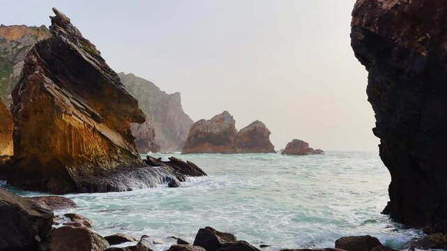 Beautiful rocky coast beside the Atlantic. The popular Portuguese Ursa Beach. Beautiful panoramic view of the rocky shore with incoming blue waves. Beautiful ocean against a background of rocks.