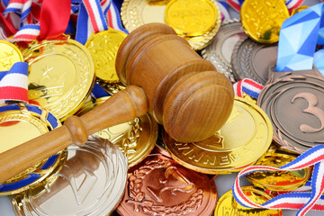 Sport court concept. Wooden judge gavel on many medals background close-up.
