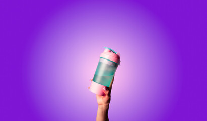 Hand holds a sports shaker. Female hand holds a protein shaker, copy space.