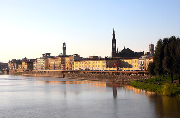 Buildings of Florence in Italy with towers of historic monuments and the wide Arno river at sunset