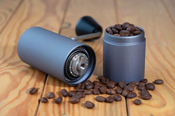 Manual coffee grinder and portafilter on wooden background with roasted of coffee beans.