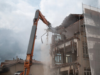 demolisher is demolishing the facade of a building, building demolition
