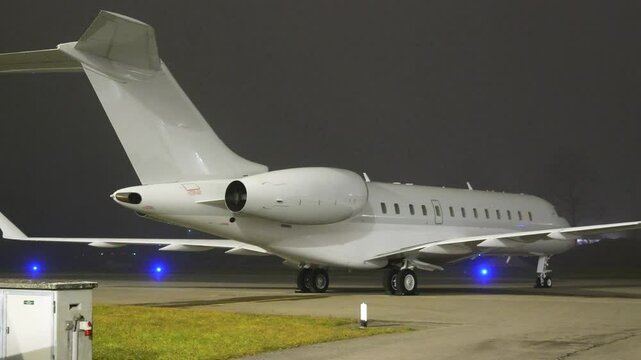 white unmarked private jet designed for long haul flights parked apron fbo gat stands aircraft during dark night airport panning shot long-haul area 