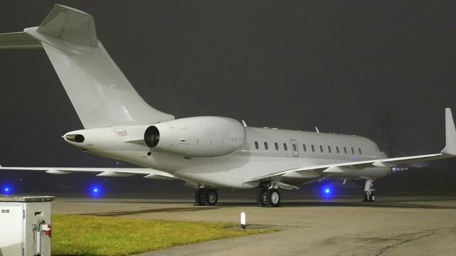 white unmarked business jet parked apron fbo gat stands heavy highlighted during night airport panning shot private aircraft area scene 