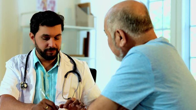 Indian Asian handsome male doctor prescribing medications to a senior old-aged male patient in his OPD, carefully explaining dosage, treatment plan in cozy clinic, ensuring professional healthcare