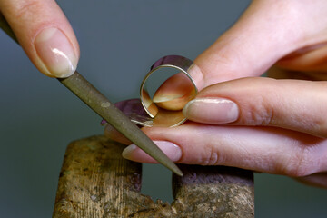 Profession jeweler. The photograph shows a close-up of the hands of a person working on a product. Making jewelry by hand. Handwork. Close-up.