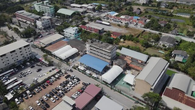 High angle shot of a busy city intersection with various vehicles and buildings. Trees and houses surround the roa