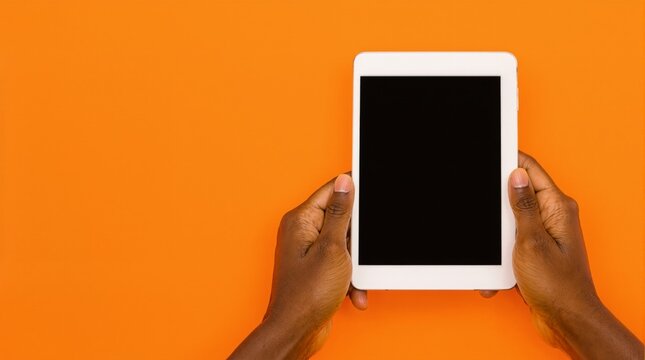 Hands holding a white tablet with a blank screen on a bright solid orange background, representing a mockup or template for design space. Ai generative.