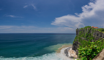 Uluwatu Temple in Bali the land of the Gods. Sitting on top of a forest cliff overlooking turquoise blue beach. beautiful colourful skies of Bali island Indonesia 