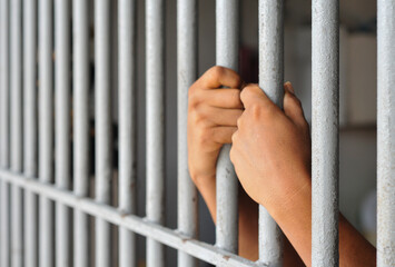 Obraz premium prisoner's hands behind bars with black background 