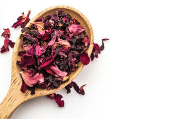 Obraz premium A wooden spoon filled with vibrant dried hibiscus petals against a white background, highlighting their rich red and purple hues.