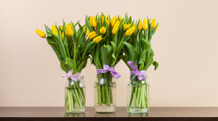 Yellow tulips in glass jars on neutral background