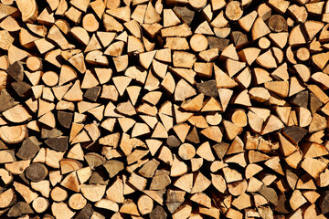 On a sunny morning, a neat stack of firewood, prepared for heating the house, is flooded with sunlight (from the series 