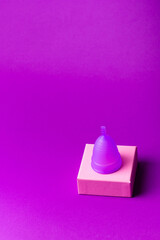 Menstrual cup to create protection during menstruation. Feminine hygiene concept. Women's health. Menstrual cup on violet background. Hygiene products for women.