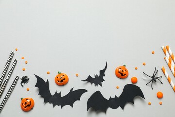 Different Halloween decorations including pumpkins, spiders and bats with confetti on gray background