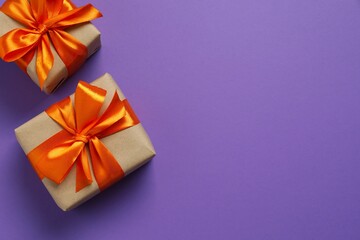 Top view photo of giftboxes with orange satin ribbon bow on color background 