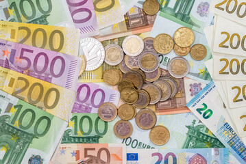 pile of European currency paper euro banknotes with metal coin, top view