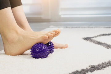Woman is training with foot massage ball from muscle pain and stress. Relaxation massage after hard work day.