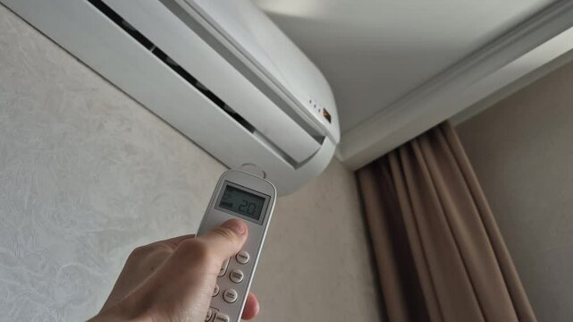 Man turns on air conditioner with remote control, close-up