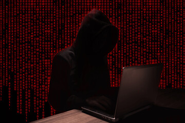 Hooded Silhouette of Hacker using a laptop on red binary code background