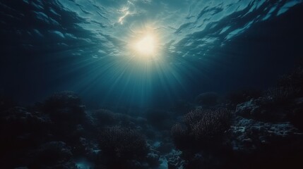 Obraz premium Sunbeams penetrate the dark blue ocean water, illuminating underwater coral reef. Dark, moody, underwater scene.