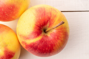 Three juicy apples on a wooden table, close-up, top view.