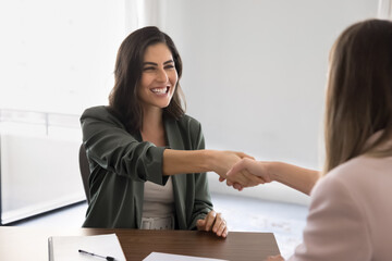 Happy Hispanic woman shaking hands partner start or finalize formal meeting successfully in office,...