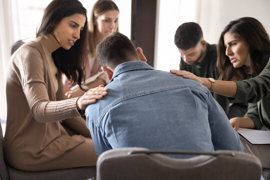 Group of teammates comforting male colleague after failure or dismissal, offering emotional support, solidarity, touch his shoulder as gesture of empathy and understanding. Psychological aid community