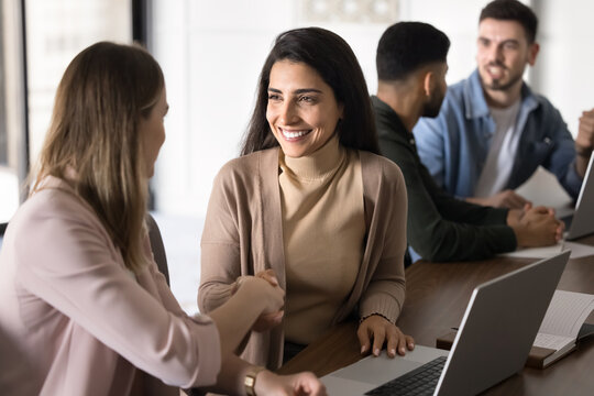 Two businesswomen shake hands in office, celebrating completion of successful project or joint goal, recognizing and appreciating guidance provided, demonstrating unity, mutual commitment and respect