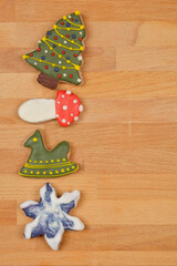 A top-down view of Christmas-themed cookies, including a Christmas tree, mushroom, rocking horse, and star, arranged in a row on a wooden surface