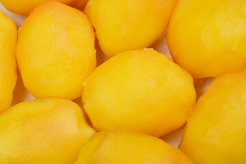 A close-up, top-down shot of several cooked yellow potatoes, revealing their texture and golden hue