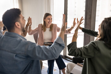 Group of teammates gather in circle giving celebratory high-five, share success and achievements....