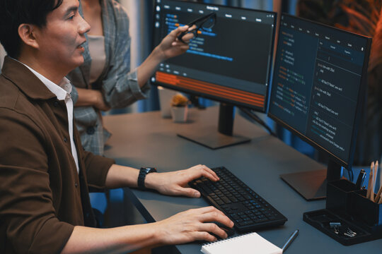 IT developers discussing with point to intelligent website development coder system running data online two screens information technology at neon light room at modern office. Infobahn.