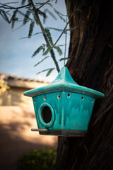 blue teal birdhouse hanging from a tree