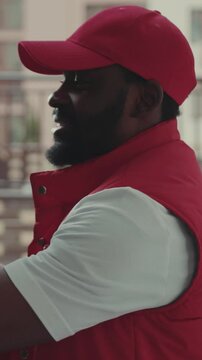 Close up courier African American gives a parce to woman after signing on delivery device cardboard technology box order post postal service device sunny beard covered load logistic mailman