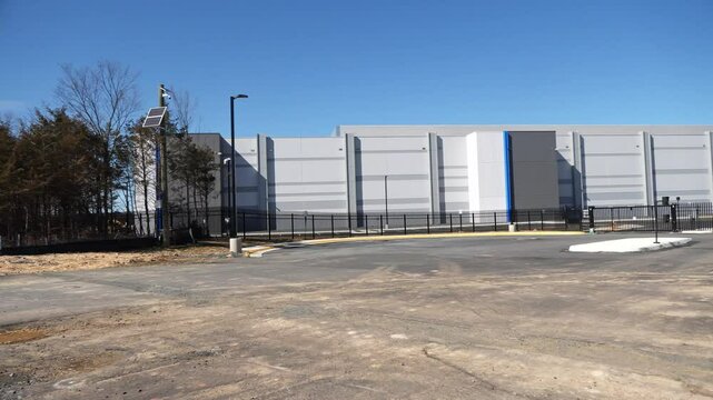 A left to right panning shot of a data center building under contruction nearing completion. A gate and fence can be seen.