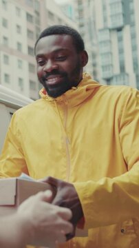 courier African American gives a parce to a man after signing on delivery device cardboard technology box order post postal service device sunny beard covered load logistic mailman