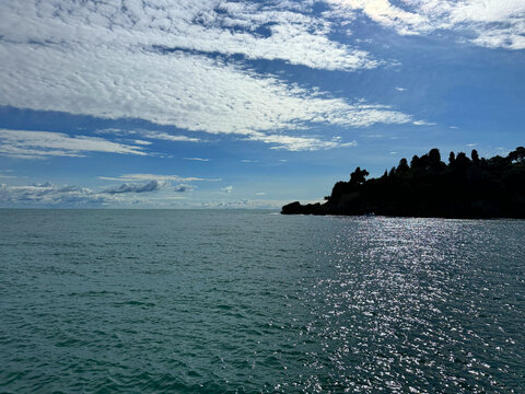 Glittering ocean, rocky coast and beautiful cloudy sky 