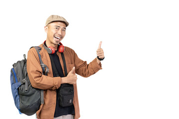 Excited young Indonesian man giving thumbs up to camera, travel concept, isolated on white background.