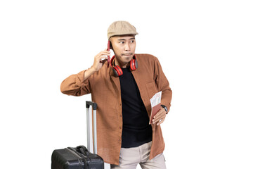 Young Indonesian male traveler is on voice call while carrying suitcase while traveling, travel...