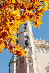 View of the spire of the church in the medieval Gothic style in the autumn park, the tops of the towers. Gothic chapel. Autumn