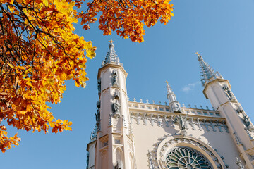 View of the spire of the church in the medieval Gothic style in the autumn park, the tops of the towers. Gothic chapel. Autumn