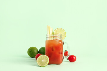 Mason jar of bloody mary with celery and lime on green background