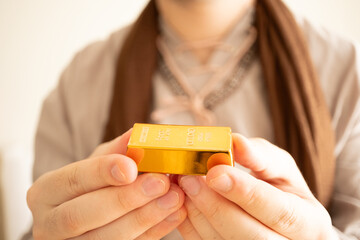 Saudi Arabian peasant in costume holds out gold bars